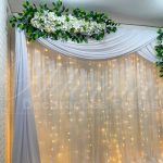 Aluguel de Painel de Cortinas Branco Suporte Duplo Com Cortinário, Led, Folhagens e Flores Brancas Para Decoração de Festas e Eventos. Este painel de cortinas branco