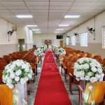 Decoração de casamento para igreja com tapete vermelho, flores brancas e colunas de vidro para eventos na Zona Sul de São Paulo.